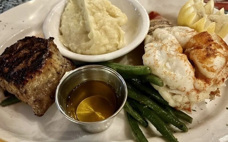 Surf and turf with grilled steak, lobster tail, mashed potatoes and green beans